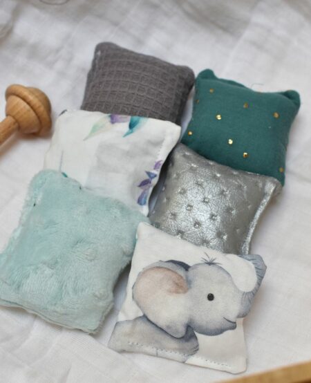 Coussin sensoriel en tissu avec différentes textures comme polaire, simili cuir et coton, pour stimuler les sens de bébé. Motif éléphant