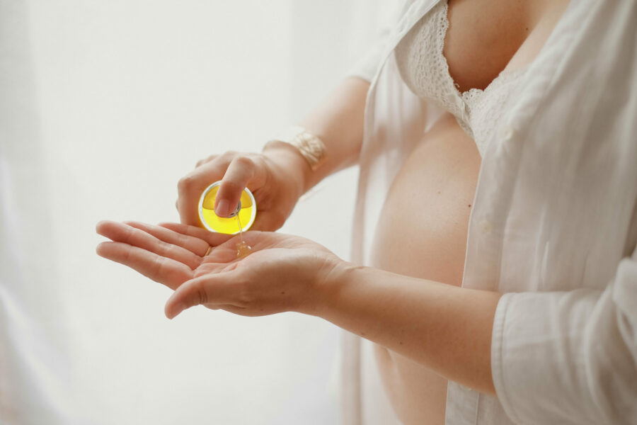 Femme enceinte qui mets de l'huile contre les vergetures dans sa main