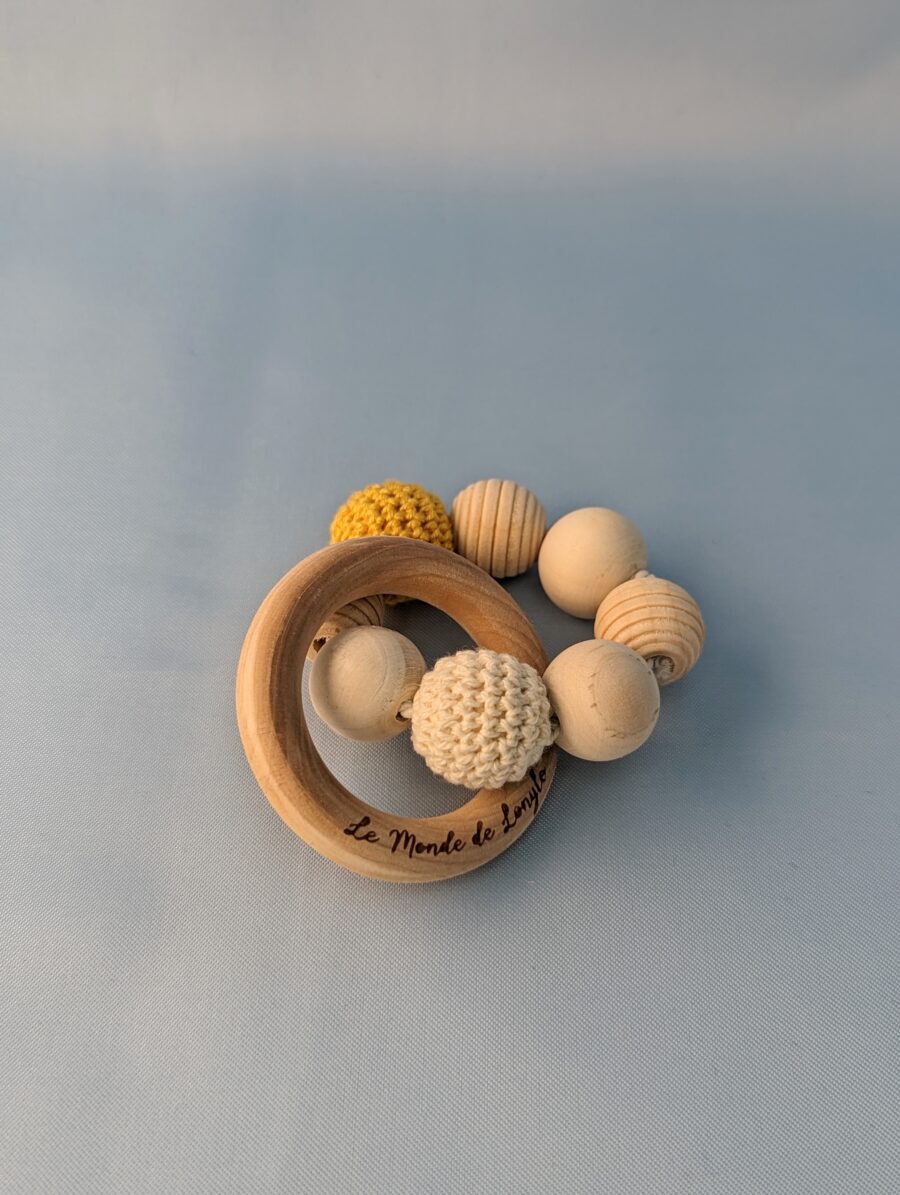 Hochet bébé en bois avec des perles en laines jaune et blanche pour soulager les poussées dentaires