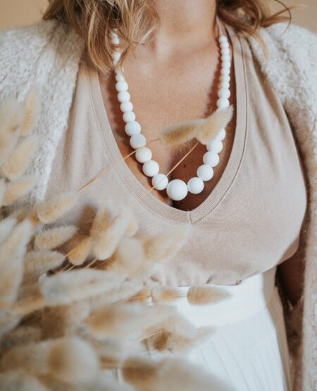 Femme qui porte le collier d'allaitement en perles blanches en silicone