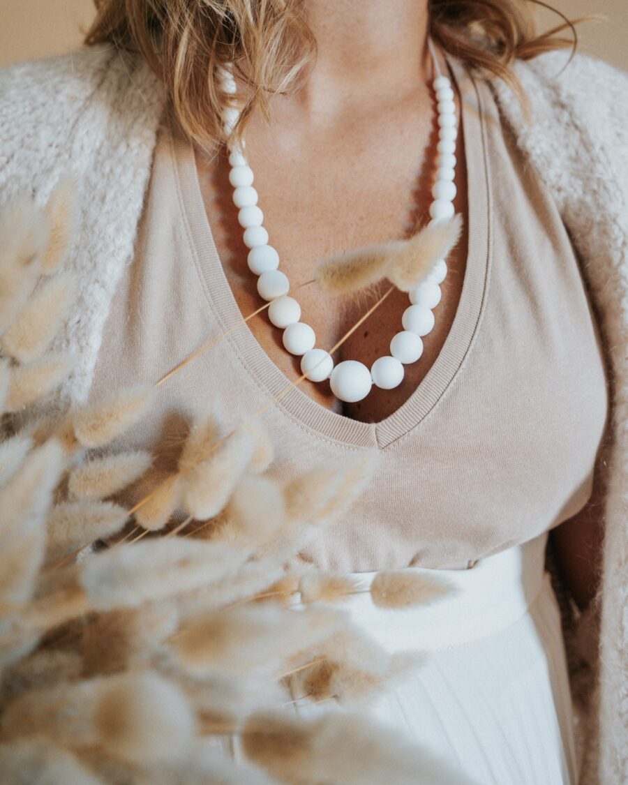 Femme qui porte le collier d'allaitement en perles blanches en silicone