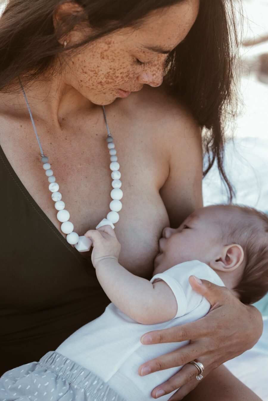 Maman qui allaite son bébé qui tient le collier d'allaitement Milk