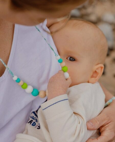 Maman qui allaite son bébé en tenant le collier d'allaitement et de portage bora bora