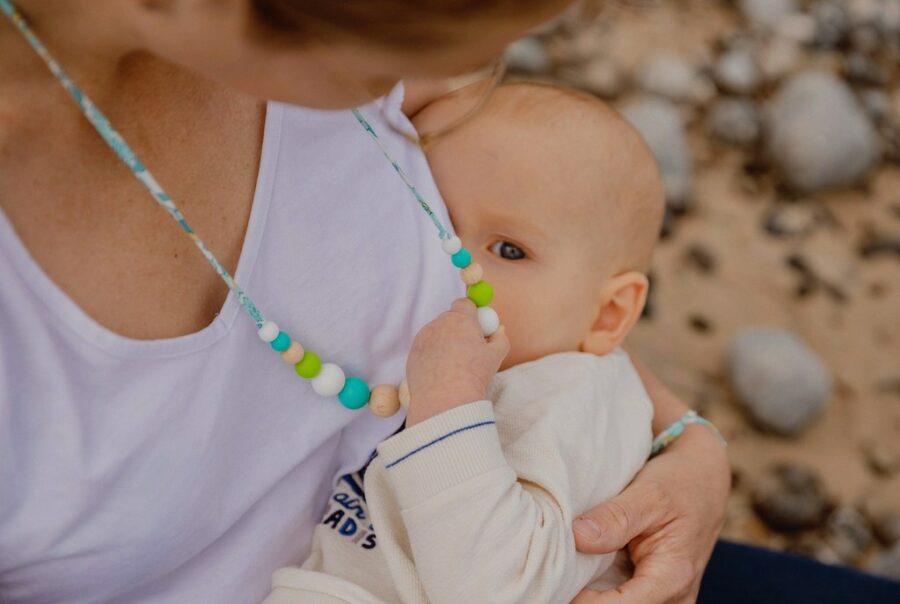 Maman qui allaite son bébé en tenant le collier d'allaitement et de portage bora bora
