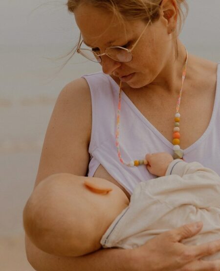Maman qui allaite son bébé avec le collier d'allaitement sorbet été couleur corail