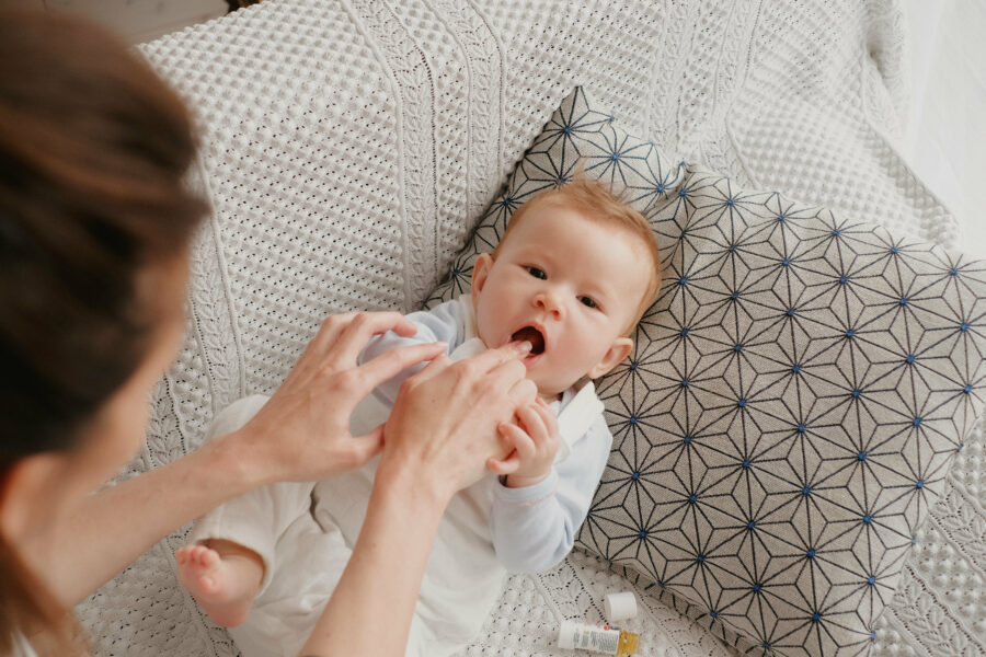 Maman qui applique de l'huile premières dents à son bébé pour soulager ses poussées dentaires