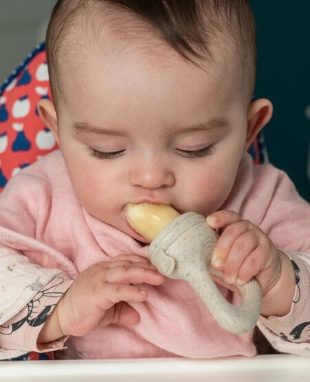 Bébé qui mange avec une grignoteuse pour soulager ses poussées dentaires