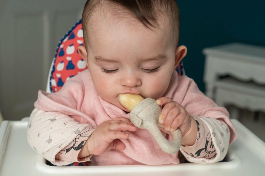 Bébé qui mange avec une grignoteuse pour soulager ses poussées dentaires