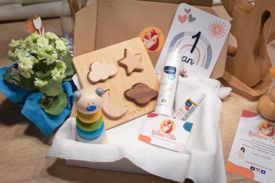 Box bébé avec abonnement qui contient : un puzzle en bois, une carte étape, une crème apaise peau, une tour en anneau, une huile badaboum