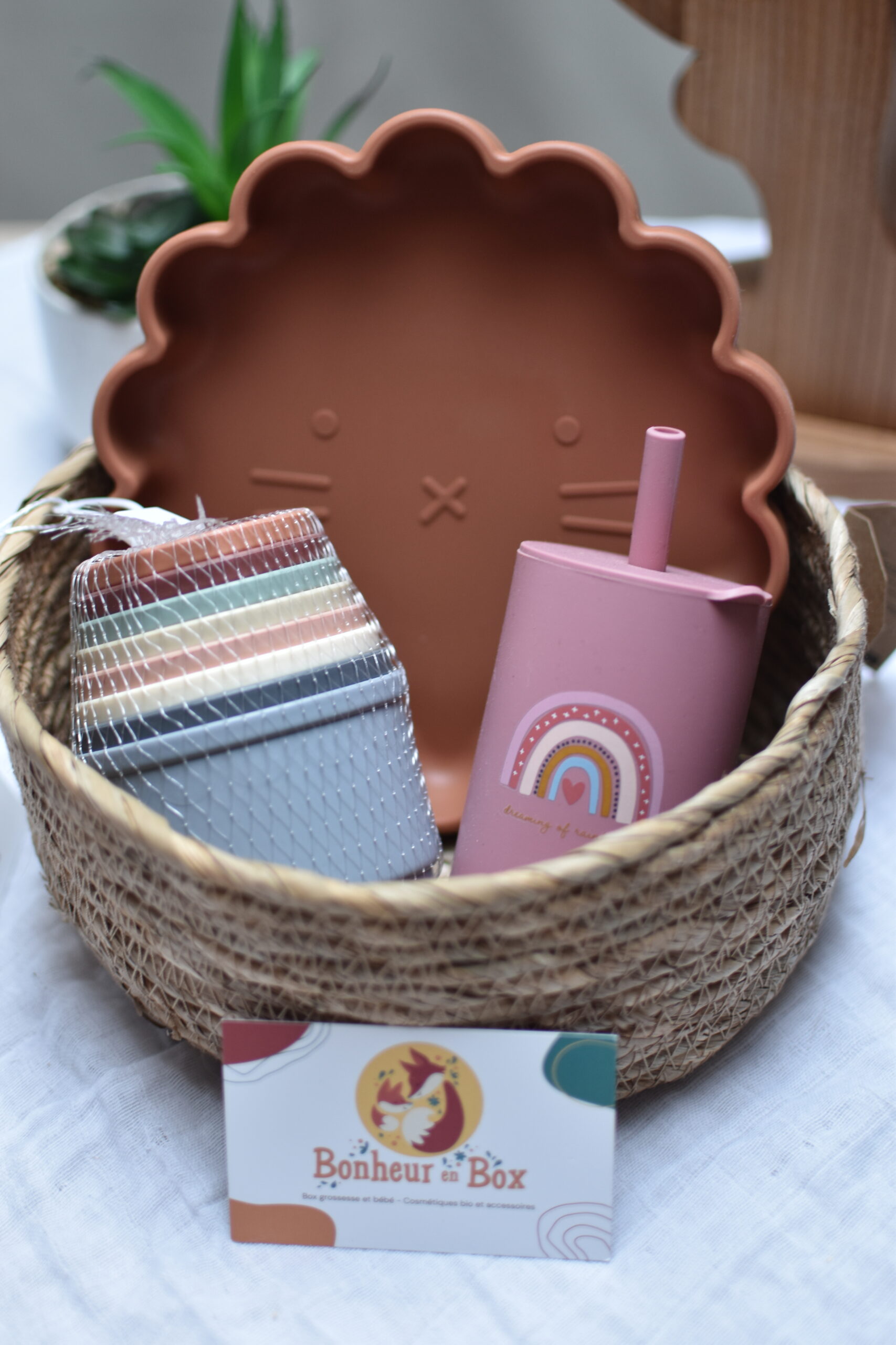 Box bébé mensuelle avec une assiette en silicone, une tour de gobelets à empiler, et une tasse en silicone.