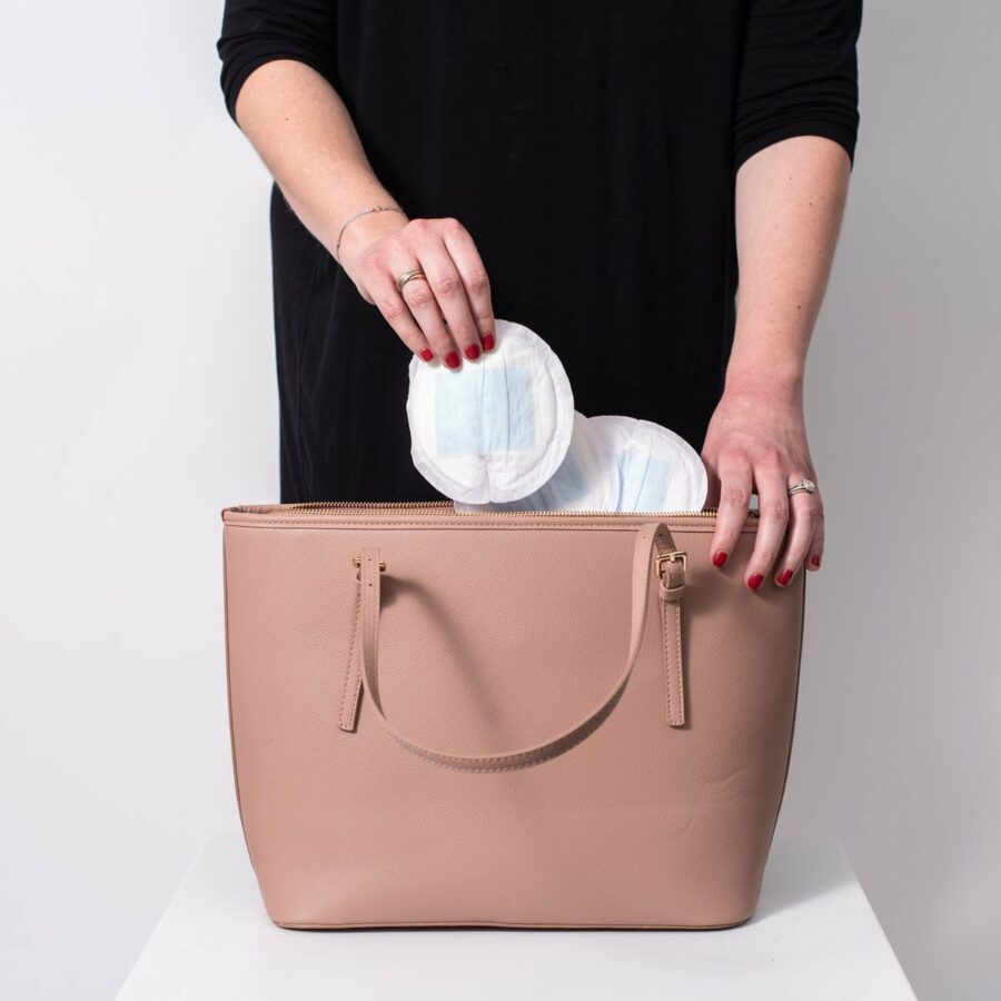 Femme qui mets ses coussinets d'allaitement jetable dans son sac à main