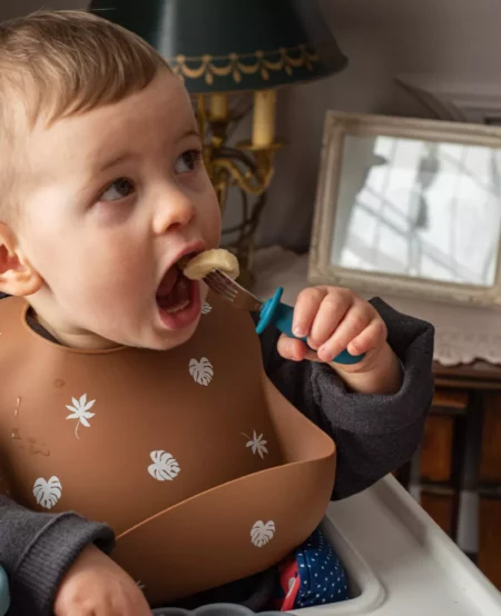 Bébé qui mange avec une fourchette métal