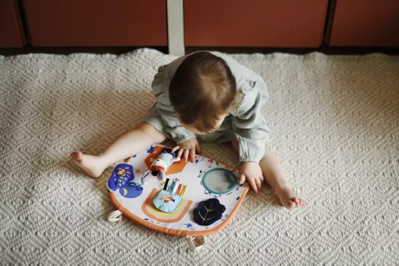 Bébé assis qui joue avec son tableau d'activité