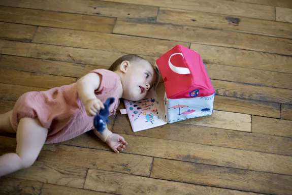 Bébé assis entrain de jouer avec sa maison en tissus et une peluche