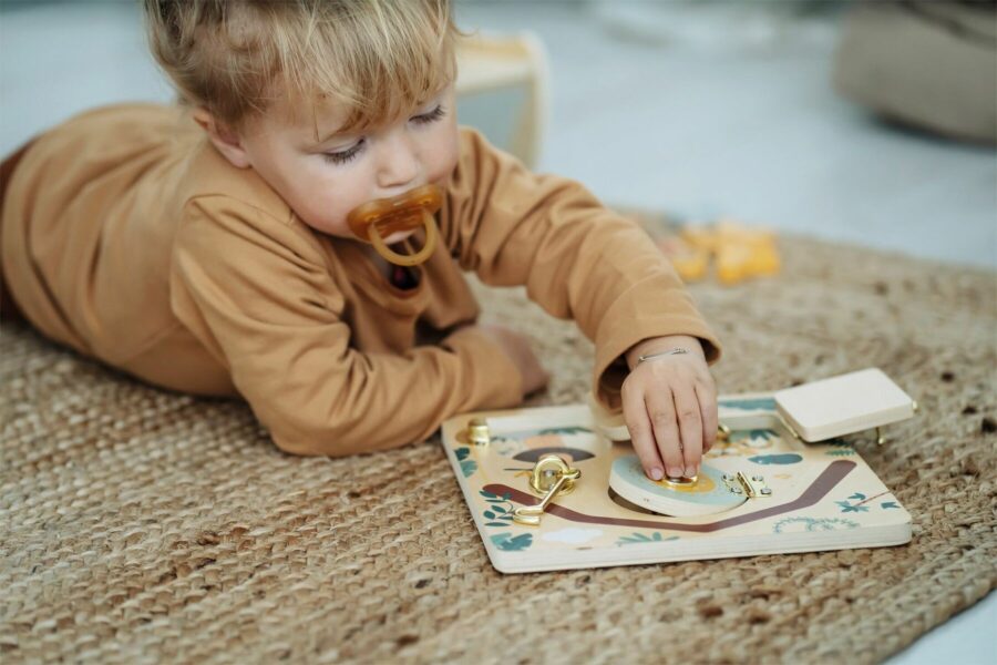 Jeu d'apprentissage : enfant utilisant la planche Montessori avec serrures