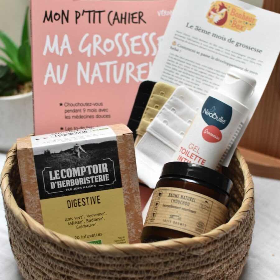 Vue d'ensemble d'une box future maman pour le 3ème mois de grossesse, comprenant une tisane digestive bio, des rallonges soutien gorge pour la poitrine qui prend du volume, un gel intime bio, un baume bio et un livre sur la grossesse au naturel.